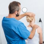 chiropractor stretching neck of woman during appointment in hospital