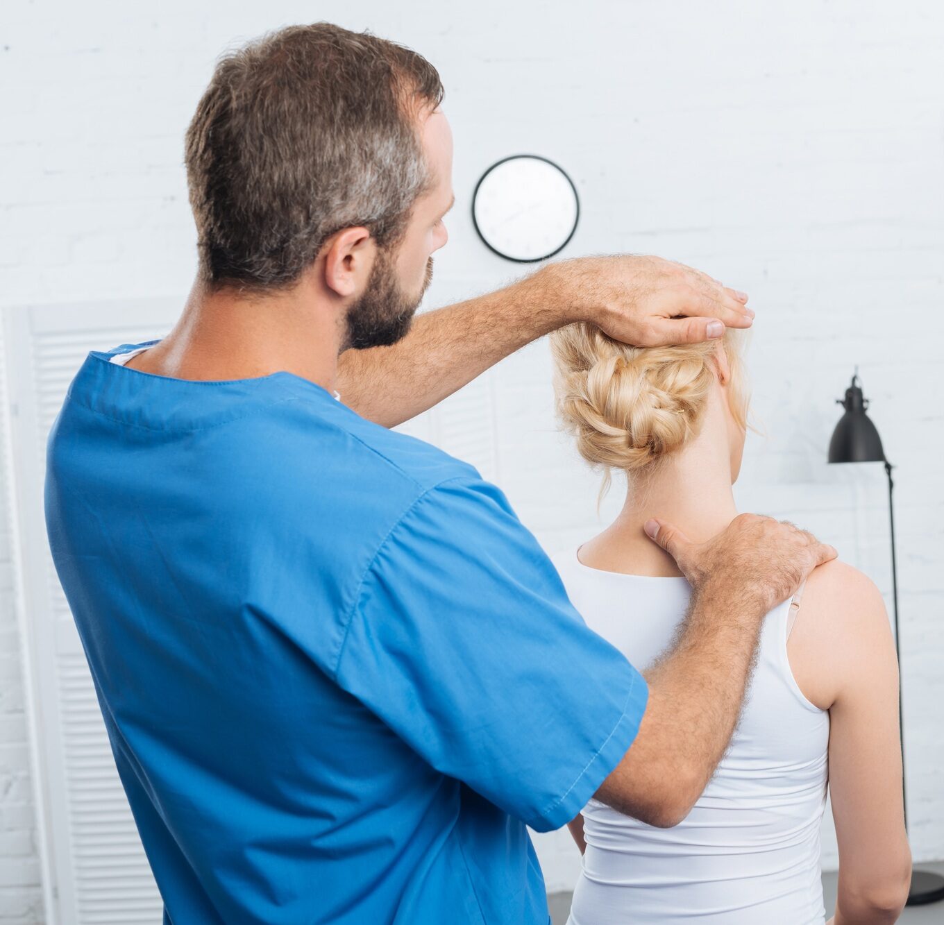 chiropractor stretching neck of woman during appointment in hospital
