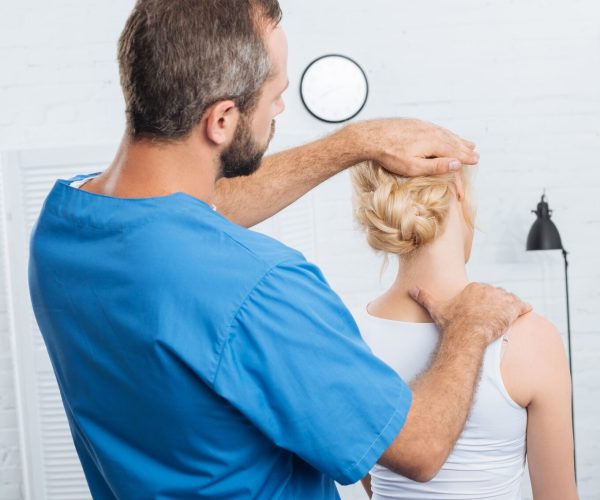 chiropractor stretching neck of woman during appointment in hospital